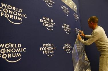 A worker sets up logos of the World Economic Forum (WEF) at the congress center in the Swiss mountain resort of Davos January 20, 2015. 