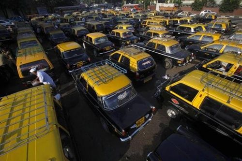 A driver stands amid parked taxis near Santa Cruz domestic airport in Mumbai.