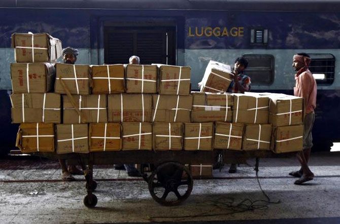 Porters transport goods on a hand-pulled trolley to load onto a train at a railway station in Kolkata.