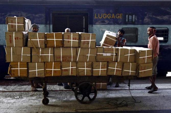 Porters transport goods on a hand-pulled trolley to load onto a train at a railway station in Kolkata.