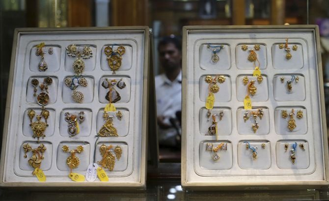 A salesman is reflected in a mirror inside a gold jewellery showroom. Adnan Abidi/Reuters