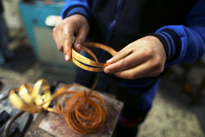 A worker holds gold bracelets at a jewellery workshop. Photograph: Mohammed Salem/Reuters
