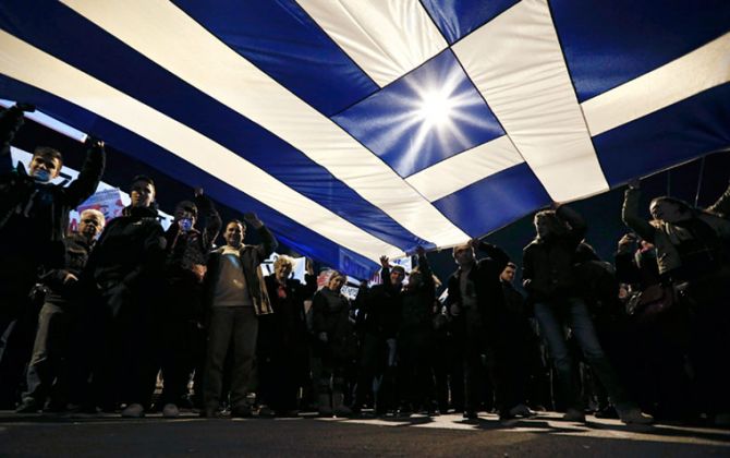 Protesters hold a giant Greek national flag during an anti-austerity and pro-government demonstration in front of the parliament in Athens February 15, 2015.