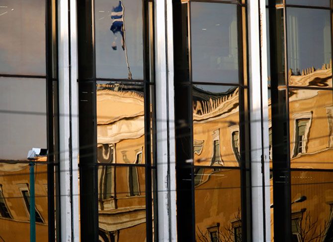 The Greek parliament is reflected on the Foreign Ministry building in Athens March 12, 2015. Greece has promised its lenders to reform its state sector, to implement labour reforms, such as opening up closed professions, to make its economy more competitive, improve its tax administration and fight tax evasion and corruption, which have been widely blamed for the debt crisis. REUTERS/Yannis Behrakis