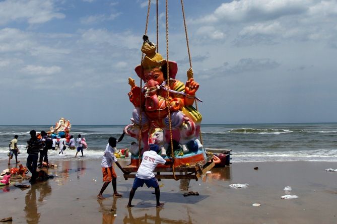 Fishermen lower an idol of the Hindu elephant god Ganesh, the deity of prosperity, for its immersion into the Bay of Bengal 