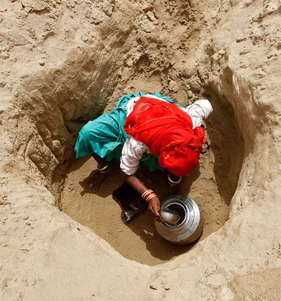 Image: A woman fills a pitcher with drinking water from a hole made in the dried-up Banas river bed near Sukhpur village, north of Ahmedabad. Villagers walk two and a half kilometres to draw drinking water from them, and they say it takes 30-40 minutes to fill a five-litre jar. Photograph: Reuters