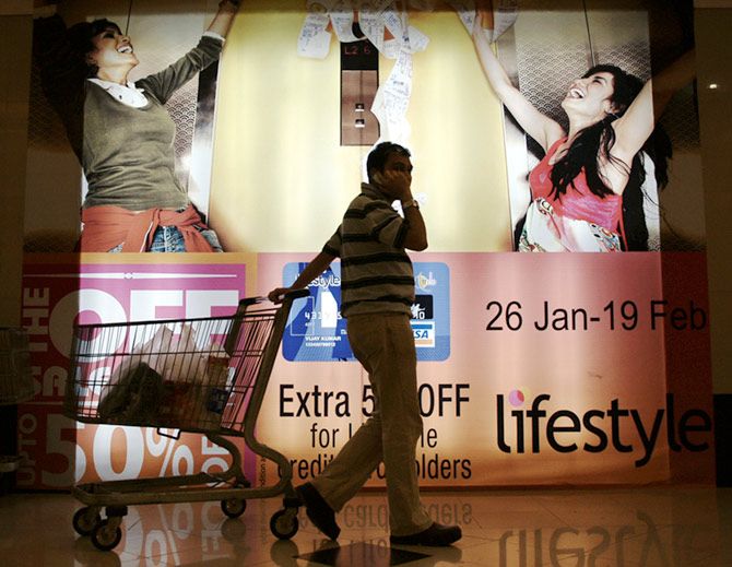 An Indian consumer pulls his trolley as he passes by an advertising display at a shopping mall.