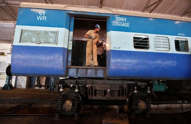 A worker welds the door of a luggage compartment of a passenger train at a railway yard in Ahmedabad