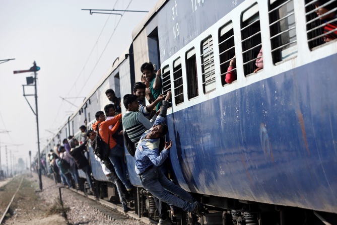 Passengers travel in an overcrowded train near a railway station at Loni in Uttar Pradesh.