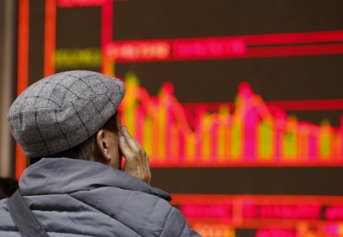 A man looks at an electronic board showing stock information at a brokerage house in Beijing, China.