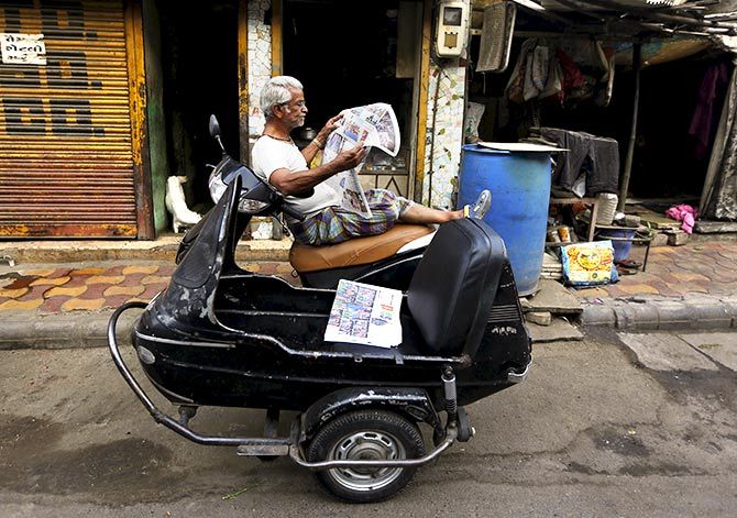 A man reads a newspaper as he sits on his scooter outside a shop in the western Indian city of Ahmedabad April 8, 2015. Photo: Amit Dave/Reuters