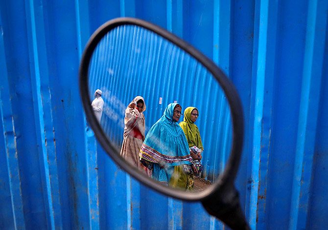 Dawoodi Bohra Muslims are reflected in the rear mirror of a parked scooter as they walk past the site of an under construction mosque in Mumbai, India, September 19, 2016. Photo: Danish Siddiqui/Reuters