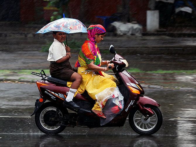 A boy holds an umbrella as he travels on a scooter with his mother during rains in Chandigarh, India, July 14, 2016. Photo: Ajay Verma/Reuters
