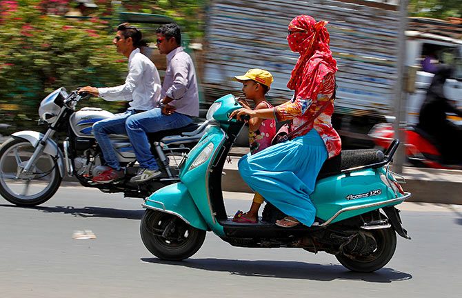 A woman shields her face from the sun as she rides her scooter in Ahmedabad, India May 20, 2016. Photo: Amit Dave/Reuters