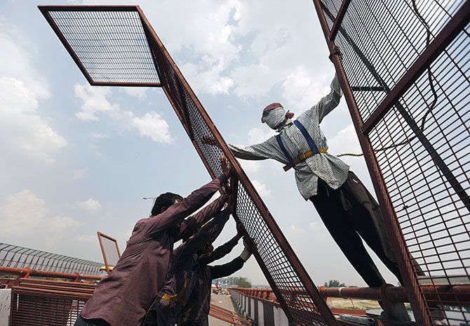 Workers install a metal fencing on a flyover to prevent people from throwing waste into the Yamuna river in New Delhi, April 7, 2016. Photograph: Anindito Mukherjee/Reuters