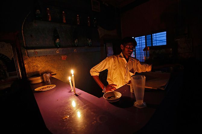 A man waits to serve customers by candle light in a country liquor bar with no electricity supply along the Nashik-Mumbai highway, about 150 km (93 miles) northwest of Mumbai, January 28, 2013. Photo: Vivek Prakash/Reuters