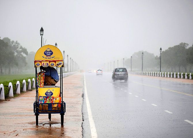 An ice-cream vendor takes shelter in his cart as it rains in New Delhi September 11, 2014. Photo: Anindito Mukherjee/Reuters