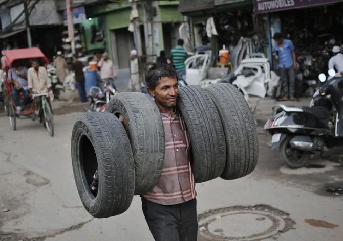 Image: A worker carries car tyres for rethreading at an automobile spare parts market in the old quarters of Delhi. Photograph: Anindito Mukherjee/Reuters