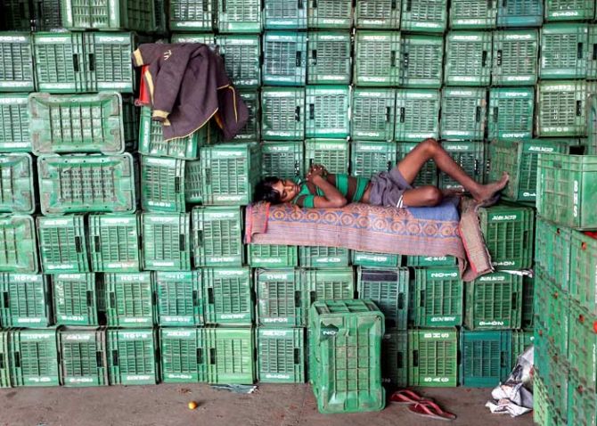 A labourer sleeps on baskets of unsold tomatoes at a wholesale market in Manchar village in the western state of Maharashtra, India, November 16, 2016. Photo: Shailesh Andrade/Reuters