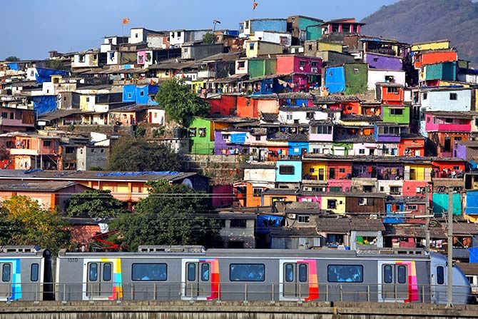 A metro train moves past a cluster of houses at the Asalpha slum in Mumbai, April 12, 2018. Photograph: Francis Mascarenhas/Reuters.