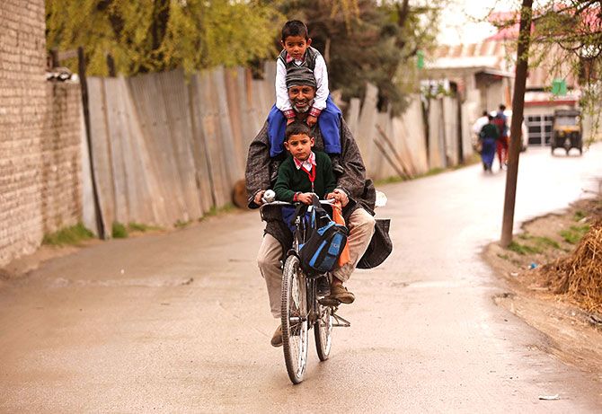 A man carries schoolchildren on his bicycle in Srinagar, Kashmir. Photograph: Danish Ismail/Reuters.