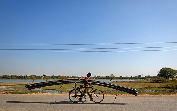 A farmer carries plastic pipes used for watering fields on his bicycle in Tonk, Rajasthan. Photograph: Danish Siddiqui/Reuters.