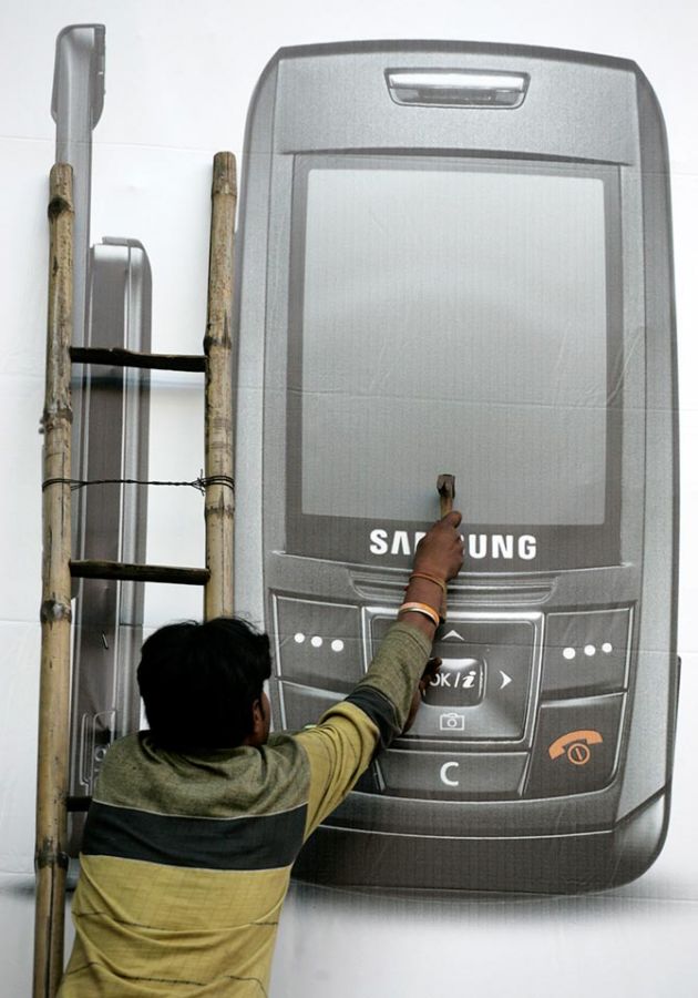 A worker puts up a billboard of a mobile phone manufacturing company in Kolkata March 5, 2007. Photograph: Parth Sanyal/Reuters.