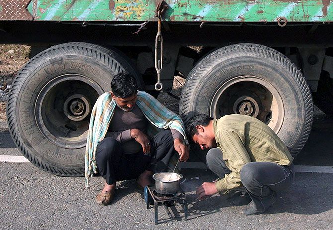 Stranded drivers prepare tea on a kerosene stove on the Jammu-Srinagar national highway. Photograph: Mukesh Gupta/Reuters.