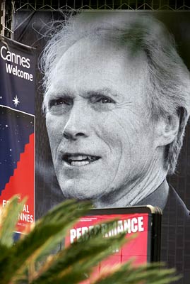 A huge image of Clint Eastwood towers over signs welcoming visitors to the Cannes film festival