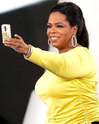 Oprah takes a picture of the crowd with her cell phone during a taping of the 24th season