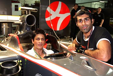 Shah Rukh Khan poses with HRT Formula One driver Karun Chandhok of India in the pits