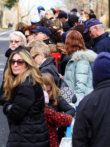 Bystanders wait for the hearse carrying the body of singer Whitney Houston outside the Fairview Cemetery