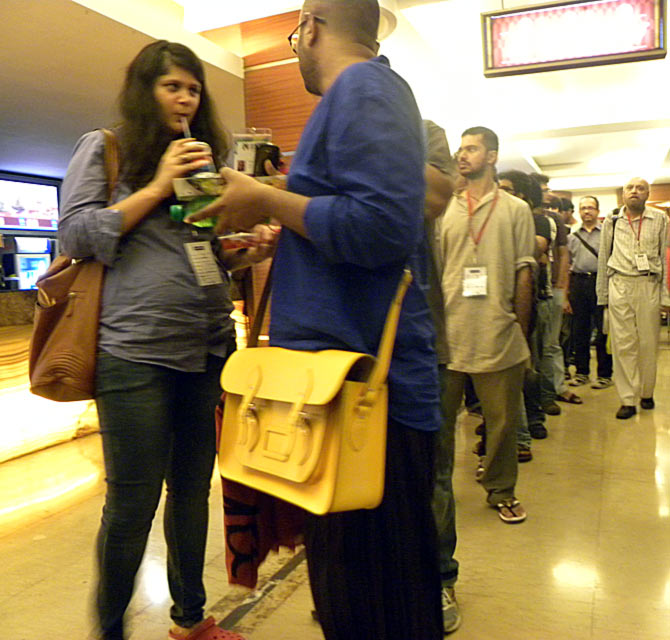 A patron, with an eye-popping satchel, talks to a friend in line for Ilo Ilo