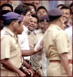 R S Sharma (bespectacled man wearing white shirt) being produced in a Pune court. Pic: Arun Patil