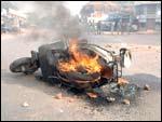 A scooter burns as policemen watch from a distance. Photo: STR/AFP/Getty Images