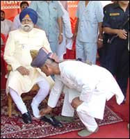 Bihar governer Buta Singh being helped by a man in removing his shoes in state function