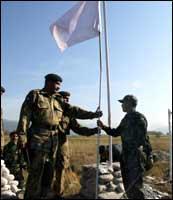 A Pakistani army officer (C) hands over a white peace flag to an Indian army officer at the Line of Control on November 7, in an historic move to help earthquake-striken people from the region.