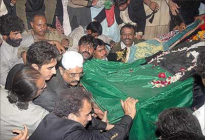 Asif Ali Zardari, husband of former Pakistan prime minister Benazir Bhutto, lowers her coffin into the grave