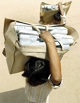Workers carry electronic voting machines from a distribution centre