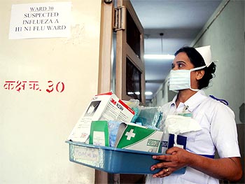 A nurse carries masks and medicine outside the influenza A (H1N1) ward in Mumbai