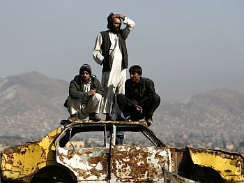 Afghan men sit on top of a wrecked car to watch a dog fight during the dog-fighting season in Kabul