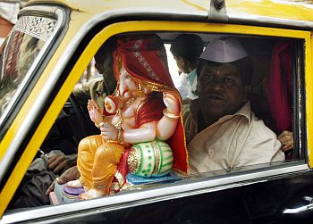 A devotee carries an idol of the Lord Ganesha in a taxi in Mumbai