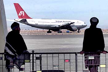 Two Taliban officials watch the Indian Airlines jet parked at Kandahar airport