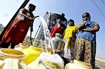 Women collect water in a slum area next to the Union Carbide Corp pesticide plant in Bhopal