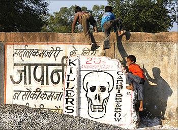 Children climb up a wall with murals which surrounds the Union Carbide pesticide plant in Bhopal