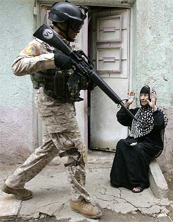 An Iraqi soldier passes a woman during a military operation in Baghdad's al-Fadhil district