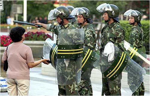 Chinese soldiers tell a woman to move on as they enforce a curfew in Urumqi