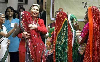 Clinton embraces a member of 'Sewa', a women's self employment voluntary organisation