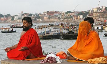 Holy men pray on the banks of river Ganges during the start of a solar eclipse in Varanasi, Uttar Pradesh