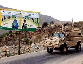 An armoured vehicle of the US army drives past an election sign in the valley of Kunar River in Afghanistan's Kunar province.